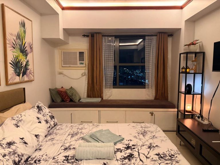 Habitación doble con ventanal y vistas nocturnas de la ciudad en Skyline Luxe Cebu Staycation