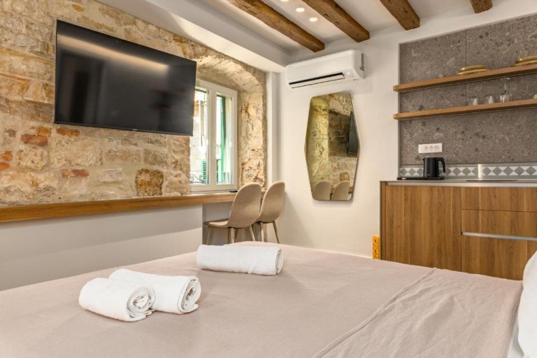 Habitación doble con pared de piedra histórica y cocina integrada en Diocletian's Suites Centre Palace