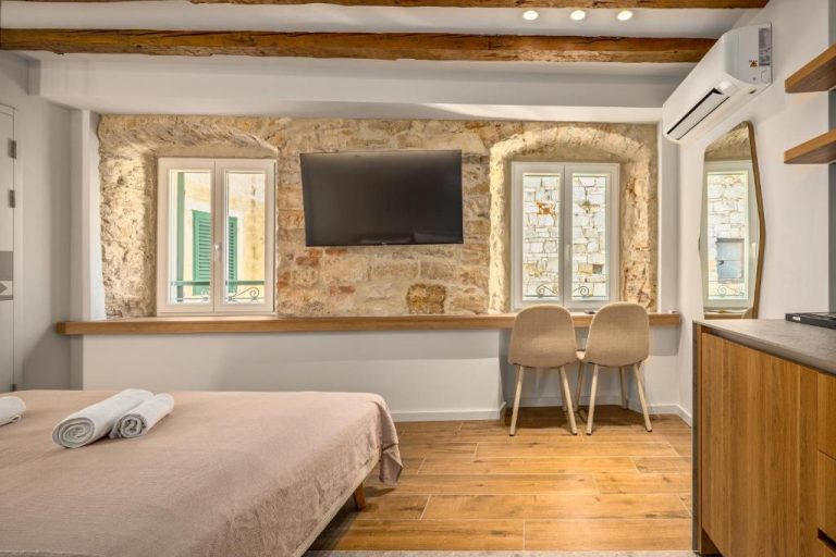 Habitación doble con pared de piedra y TV en Diocletian's Suites Centre Palace, Split