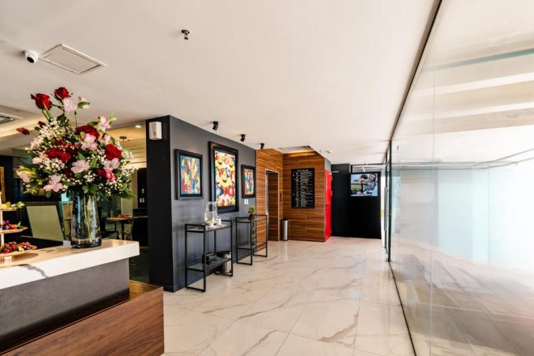 Lobby elegante con arte moderno y flores en Ramada Suites by Wyndham Asunción Aeropuerto