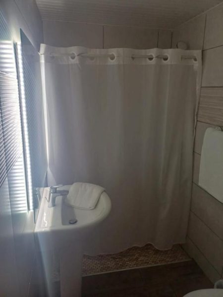 Baño moderno con lavabo y cortina de ducha blanca en Airport Hotel