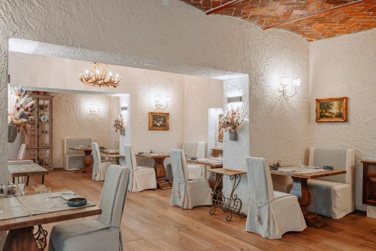 Elegante restaurante interior con mesas de madera y sillas tapizadas en Monastero di Cortona Hotel & Spa