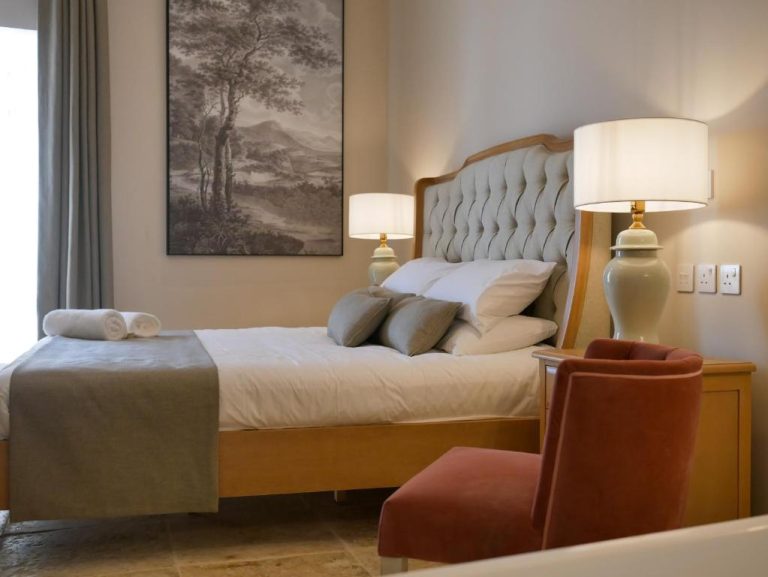 Habitación doble clásica con cama tapizada y lámparas elegantes en Battery House Hotel