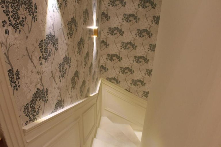 Elegante escalera con papel pintado floral y panelado blanco en Sterling Luxury Suites Valletta