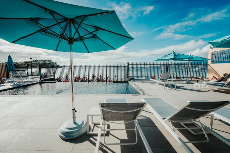 Piscina infinita con tumbonas y sombrillas azules del Boutique-Hôtel Culture Créole con vistas al mar