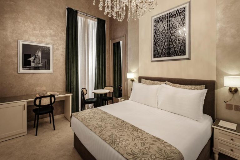 Habitación doble de lujo con cama king size y araña de cristal en Sterling Luxury Suites Valletta