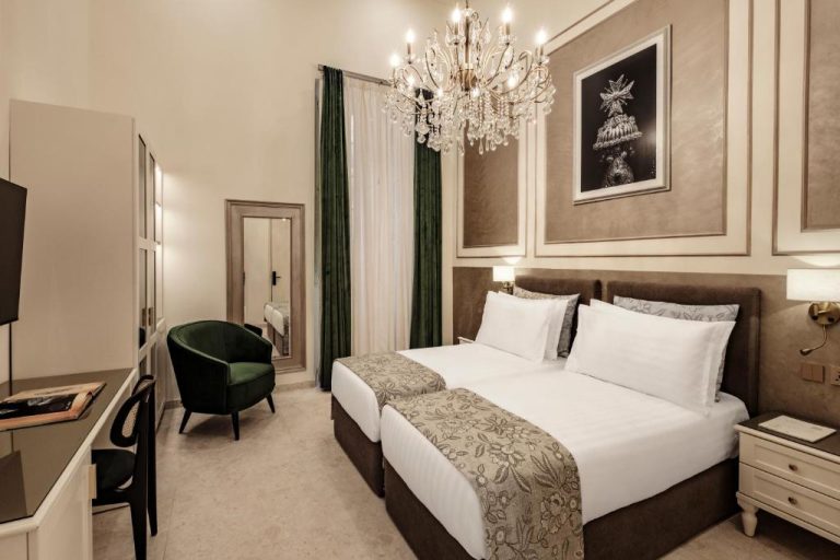 Habitación doble de lujo con lámpara de araña y cama king en Sterling Luxury Suites Valletta