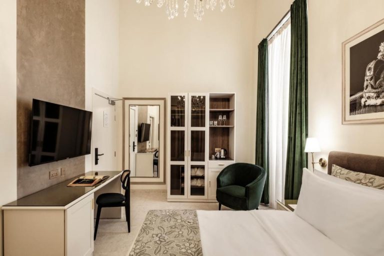 Habitación de lujo con cama doble, TV y decoración elegante en Sterling Luxury Suites Valletta