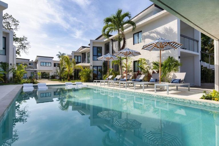 Piscina exterior con tumbonas y sombrillas del Negril Footprints Hotel rodeada de palmeras tropicales