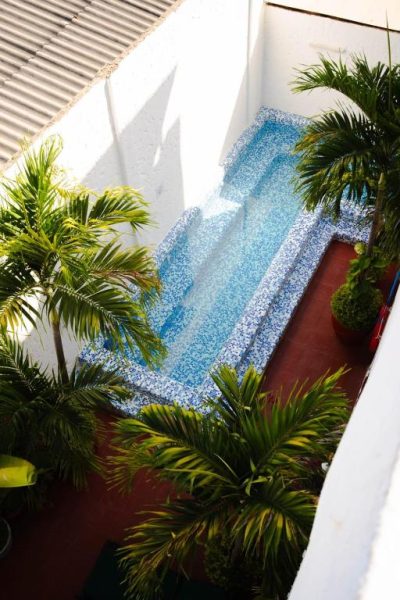 Piscina interior con mosaico azul y palmeras tropicales en el Hotel Kartaxa