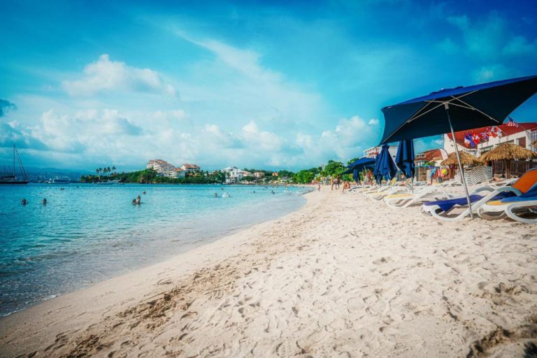 Playa de arena blanca con tumbonas y sombrillas azules del Hotel Bambou frente al mar Caribe