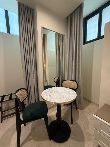 Rincón de salón con mesa de mármol y sillas de ratán en Sterling Luxury Suites Valletta