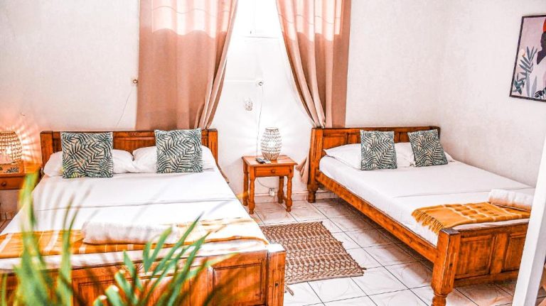 Habitación doble con camas de madera y decoración tropical en Hotel Oasis