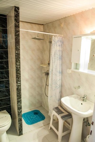 Baño completo con ducha de lluvia, lavabo y cortina floral en el Hotel Ilios and Irene