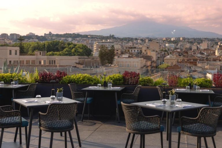 Terraza restaurante del Palace Catania UNA Esperienze con vistas al Etna y la ciudad al atardecer