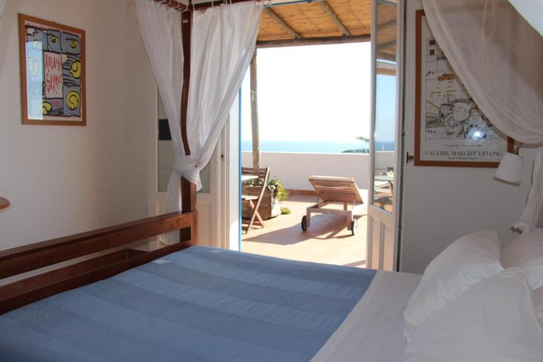 Habitación con dosel y terraza con vistas al mar en Marettimo Residence, con tumbonas y cielo despejado