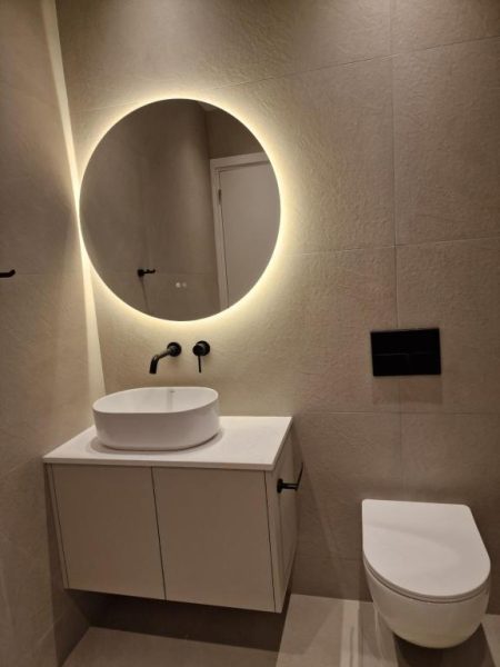 Baño moderno con espejo retroiluminado circular y lavabo sobre encimera en Hotel Hypnos Park View