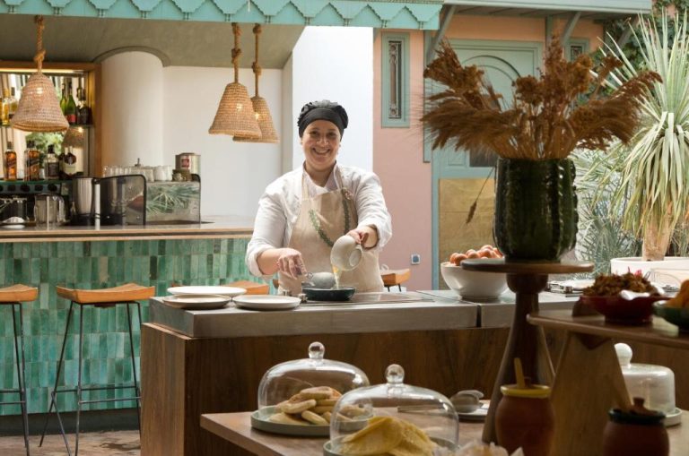 Chef cocinando en el restaurante de Les Jardins de la Médina con decoración colorida y barra de bar