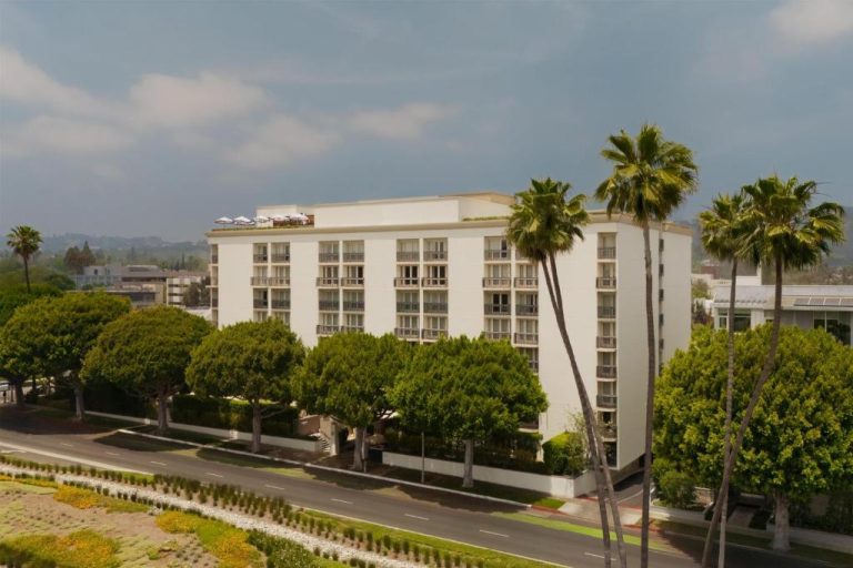 Vista exterior del hotel L'Ermitage Beverly Hills con terraza en azotea y palmeras en Los Ángeles