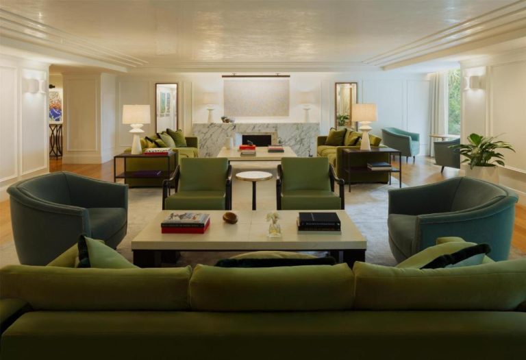 Amplio salón principal con sofás verdes y sillones azules en el hotel L'Ermitage Beverly Hills