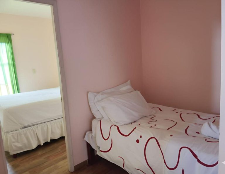 Habitación doble con dos camas individuales y paredes rosas en Apartotel Vera