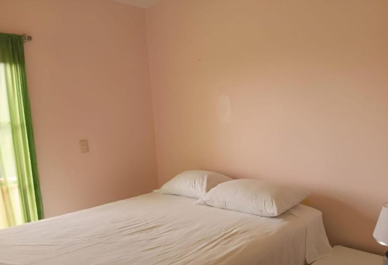 Habitación doble con cama matrimonial y ropa de cama blanca en Apartotel Vera