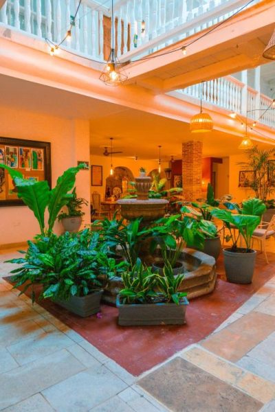 Patio interior con fuente de piedra y plantas tropicales del Hotel Kartaxa en Cartagena de Indias