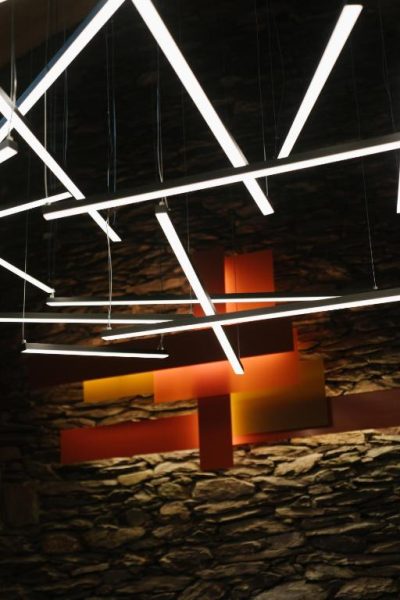 Decoración interior con luces lineales LED y pared de piedra en Trofonios Boutique Hotel