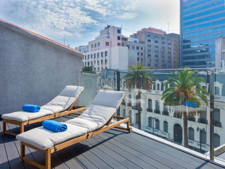 Terraza solarium con tumbonas y vistas al centro histórico de Santiago en Debaines Hotel Santiago