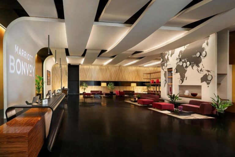 Recepción y lobby moderno del Sheraton Milan Malpensa Airport Hotel con mapa mundial y zona de descanso