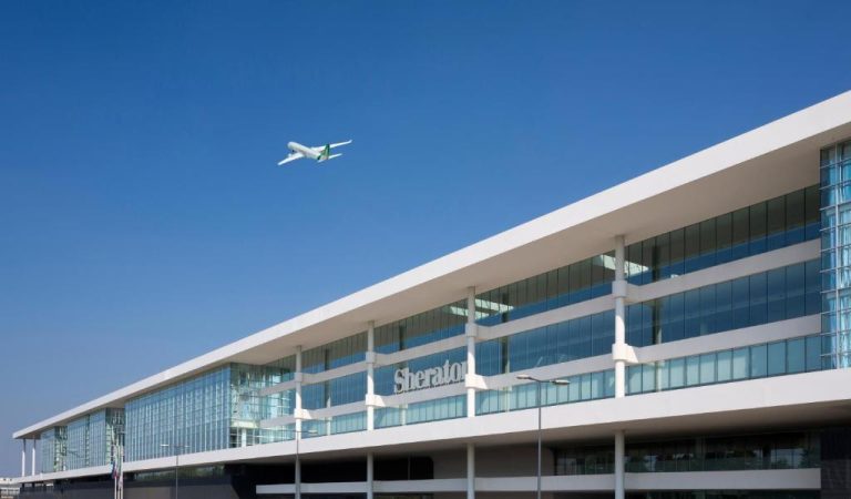 Fachada exterior del Sheraton Milan Malpensa Airport Hotel con avión sobrevolando el edificio