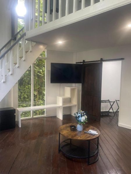 Sala de estar con loft, puerta corredera de madera y TV en LF Jungle Retreat rodeado de naturaleza