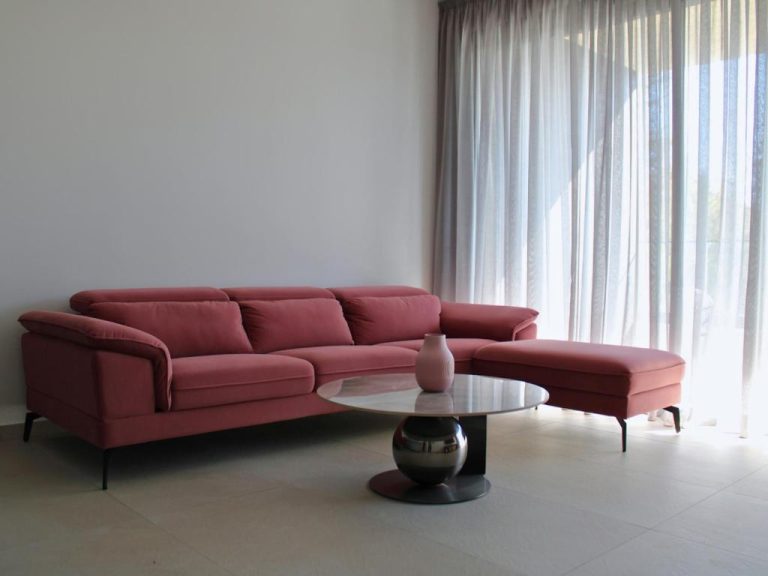 Salón moderno con sofá rinconera en rojo burdeos y mesa de centro en el Hotel Hypnos Park View