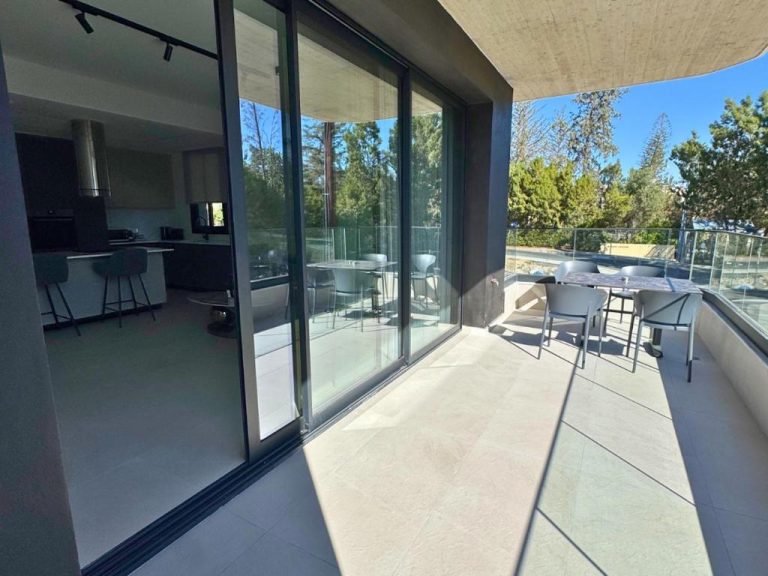 Amplia terraza exterior con mesa y sillas del Hypnos Park View con vistas a jardines y puertas correderas de cristal