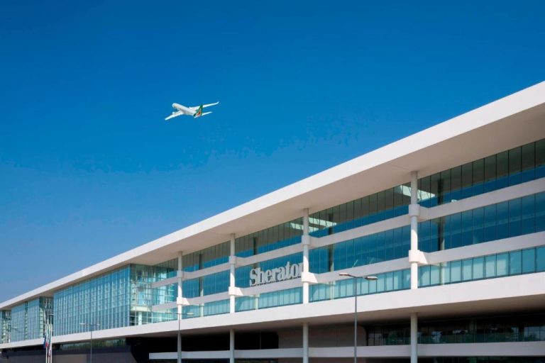 Fachada exterior del Sheraton Milan Malpensa Airport Hotel con avión sobrevolando el edificio