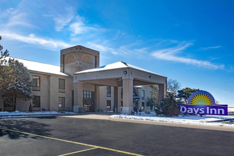 Fachada exterior del Days Inn & Suites by Wyndham Cuba con aparcamiento y nieve en invierno