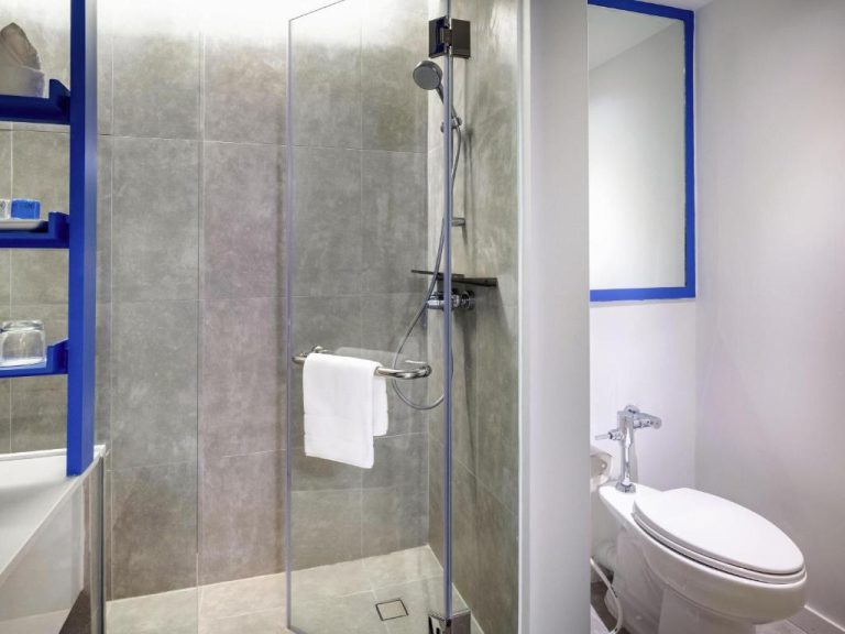 Baño moderno con ducha de cristal y toallas blancas en Novotel Rayong Rim Pae Resort