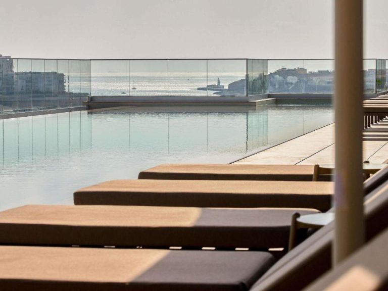 Piscina infinita con tumbonas y vistas al mar Mediterráneo en el Novotel Malta Sliema