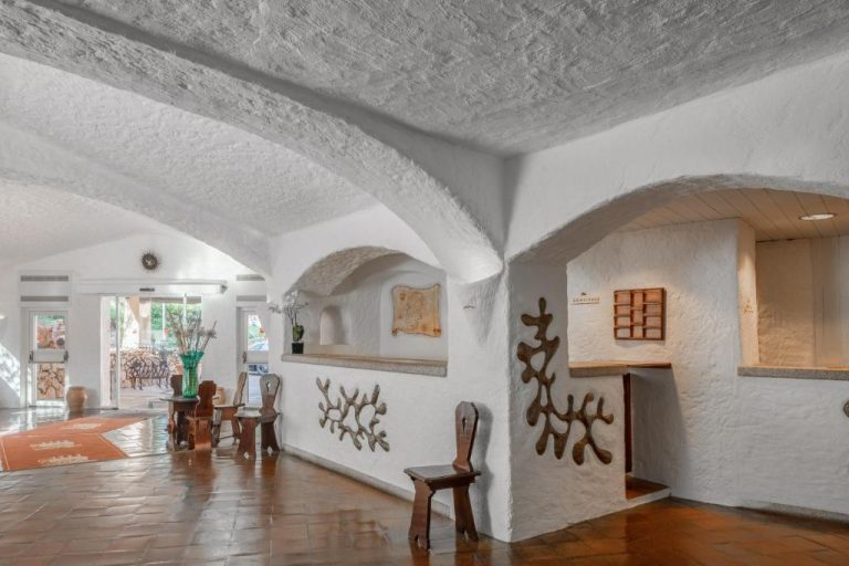 Recepción y lobby con arcos blancos y decoración rústica mediterránea del Cervo Hotel Costa Smeralda Resort