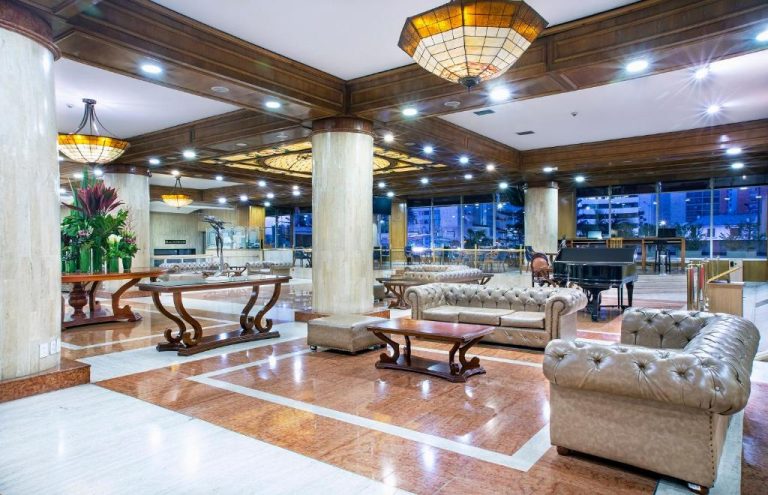 Elegante lobby del Hotel Tequendama Bogotá con sofás de cuero, piano de cola y lámparas artísticas