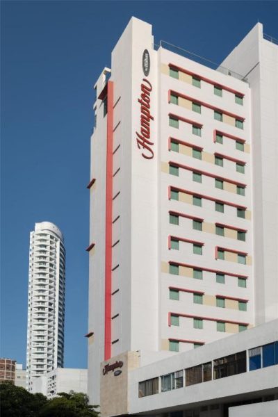 Fachada exterior del Hampton by Hilton Cartagena con su distintivo letrero rojo y arquitectura moderna