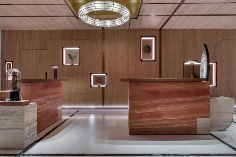 Recepción de lujo con mostrador de mármol rojo y paneles de madera en The Landmark Nicosia