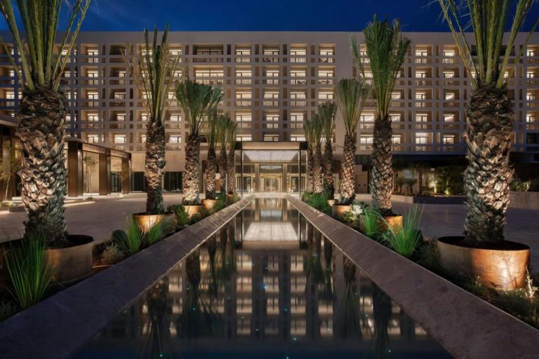 Entrada principal con piscina reflectante y palmeras iluminadas del The Landmark Nicosia Autograph Collection