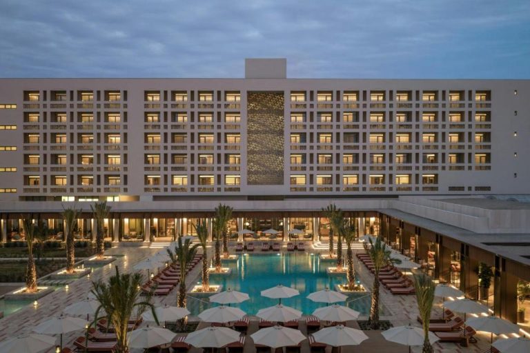 Piscina exterior con tumbonas y palmeras del The Landmark Nicosia Autograph Collection al atardecer