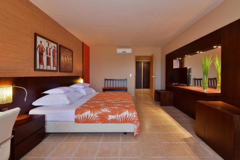 Habitación doble con decoración africana y ropa de cama naranja en el Hotel Pestana Trópico
