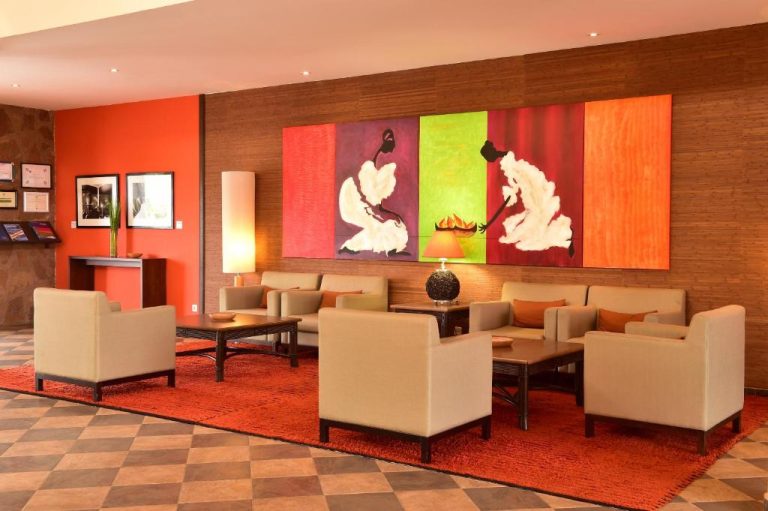 Elegante lobby y salón social del Pestana Trópico con sofás, arte africano y decoración en tonos cálidos