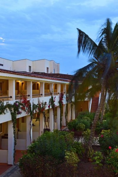 Jardín tropical con palmeras y buganvillas en la fachada del Pestana Trópico al atardecer