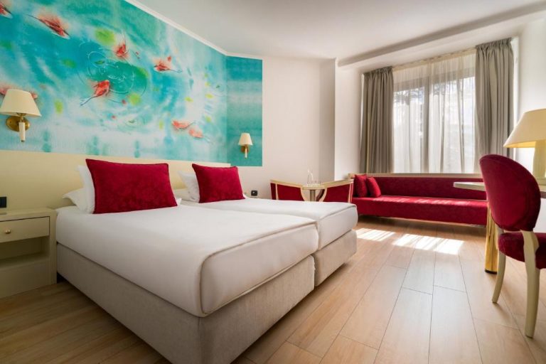 Habitación doble con camas blancas y cojines rojos en Iberostar Waves Bellevue All Inclusive
