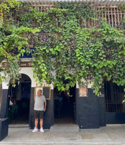 Fachada exterior del Hotel Casa Vieja cubierta de enredaderas verdes con entrada principal