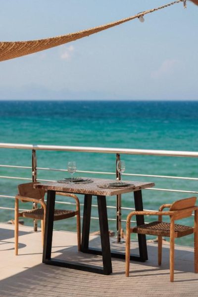 Terraza restaurante con mesa para dos y vistas al mar turquesa en Tsamis Zante Suites